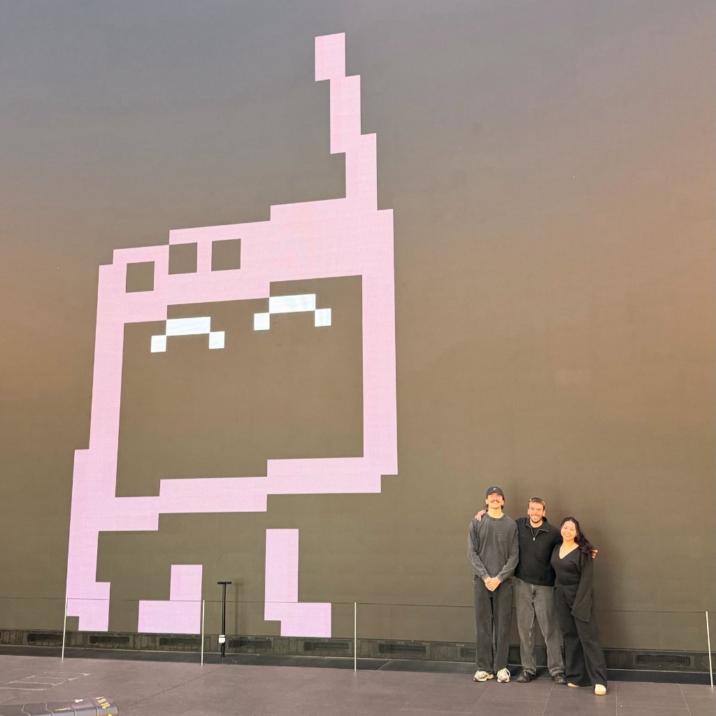 Day Zero attendees in front of the purple pixel mascot on the event screen