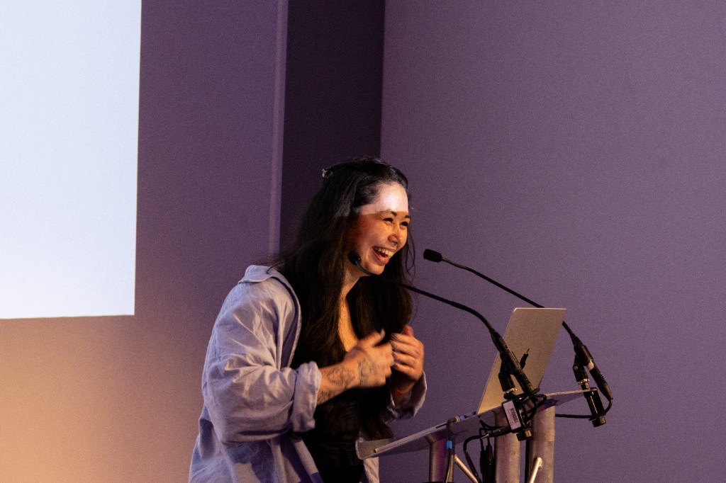 Maya speaking at Next.js Night from a podium with a headset microphone